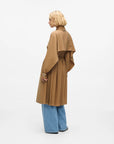 MiLA Boutique camel trench coat with cape detail, pleated skirt, and buckle cuffs. Model wears wide-leg jeans.