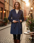 MiLA Βoutique Vetro navy blue virgin wool wrap coat with a belted waist and shawl collar worn on a city street.