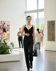 MiLA Boutique black sleeveless knit top with white contrast collar, V-neck, and gold buttons. Model wears black trousers.