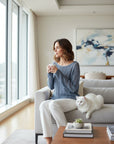 MiLA Boutique blue openwork viscose knit sweater with notch neckline and dropped shoulders, worn by a woman holding a mug.