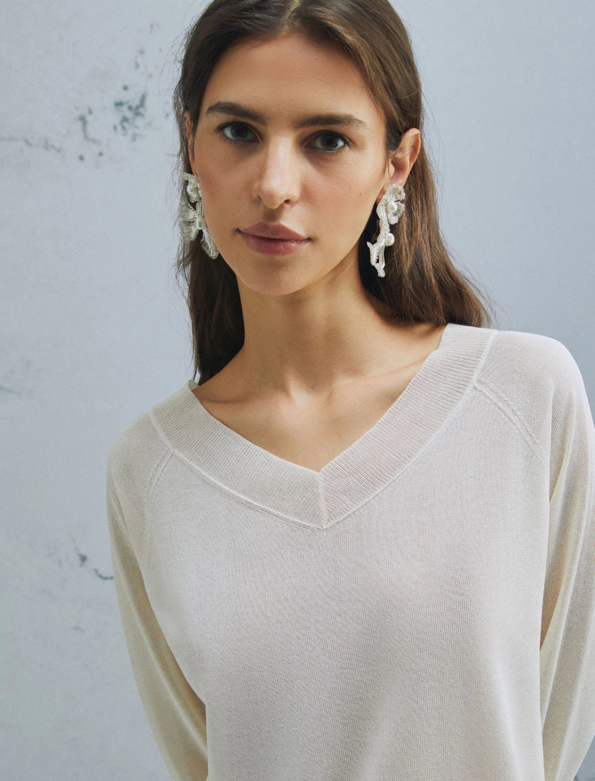 MiLA Boutique cream V-neck sweater with raglan sleeves and fine rib-knit trim. Model wears statement earrings.