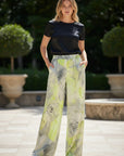 MiLA Boutique wide-leg satin trousers with a grey and lime green rose print, elasticated waistband, and side pockets.