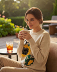 MiLA Boutique cream knit sweater with a large embroidered sunflower design on the front. Model is holding a mug.