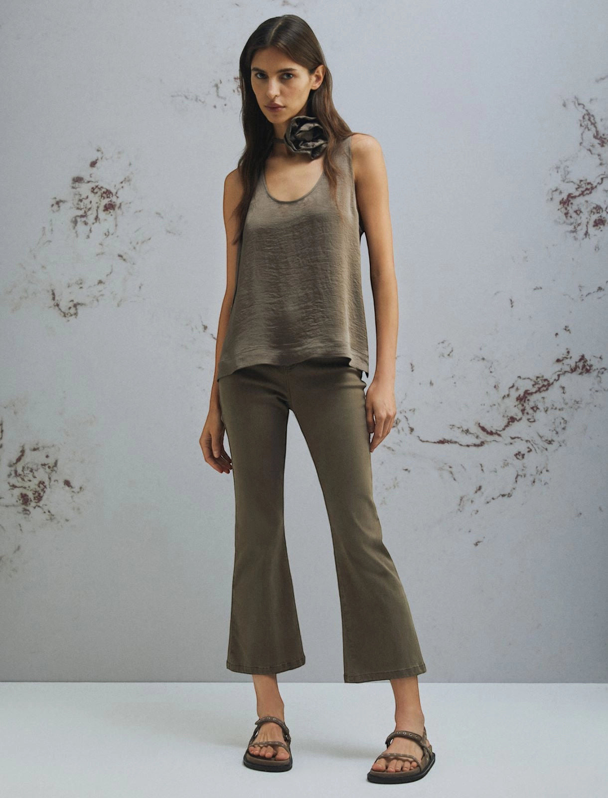 MiLA Boutique taupe crinkle twill sleeveless top with rounded neckline and matching fabric flower detail, paired with olive flared pants.