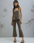 MiLA Boutique taupe crinkle twill sleeveless top with rounded neckline and matching fabric flower detail, paired with olive flared pants.