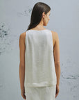 MiLA Boutique white crinkle twill sleeveless top with rounded neckline and side slits, paired with white denim skirt.