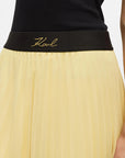 MiLA Boutique pale yellow satin pleated skirt with black elasticated waistband featuring embroidered Karl Lagerfeld signature logo.